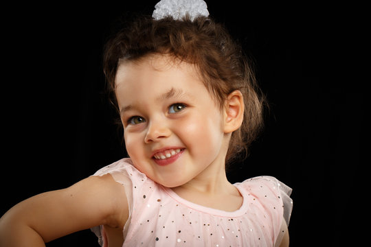 Close-up Portrait Of 3 Year Old Little Girl With Pink Dress, Shy On Black Background