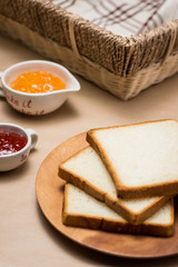 Toast with strawberry and orange jam on a plate on table.