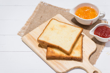 Toast with strawberry and orange jam on a plate on table.