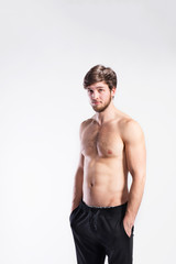 Fototapeta premium Shirtless fitness man, hands in pockets . Studio shot.