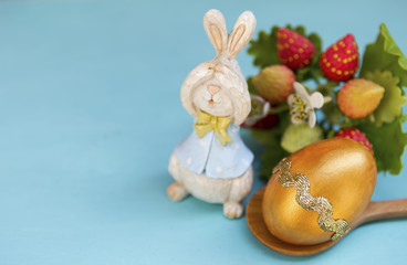 Obraz na płótnie Canvas Easter concept, Gold easter egg design with wooden bunny over blue background