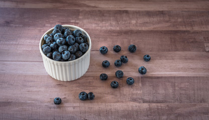Fresh tasty blueberries in a white ceramic, porcelain bowl on wooden table, surface, rustic style. Antioxidant organic superfood
