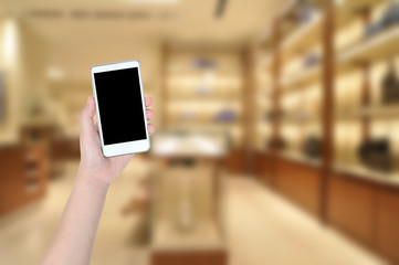 People hand holding smart phone with shopping mall soft focus, online shopping.