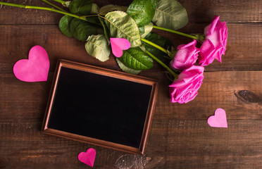 Pink roses and place for text on a wooden background