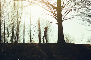 Silhouette of woman runner doing stretches before her run.