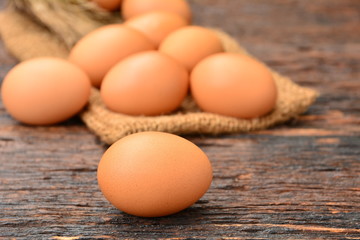 Fresh eggs put on sack on wooden background.
