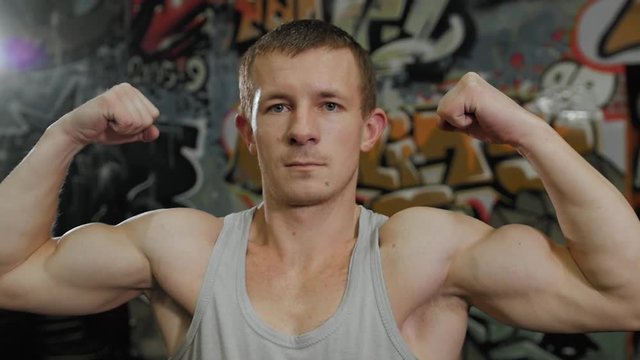 Muscular man athlete portrait standing in front of graffiti wall in crossfit center