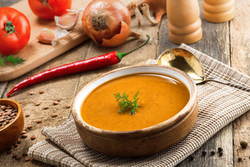 Soup made of lentil and vegetables in a rustic bowl on a canvas tablecloth. Delicious healthy vegetarian food on an old wooden table.