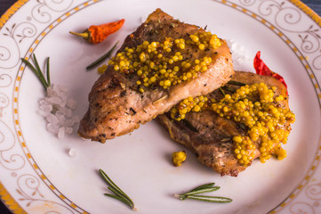 Fried meat and rosemary in a plate on a wooden background. French Orchid