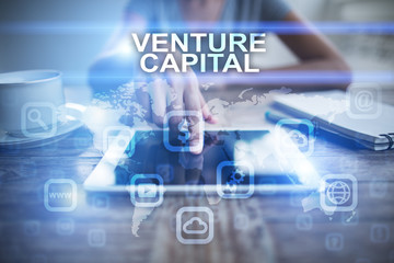Woman using tablet pc, pressing on virtual screen and selecting venture capital.