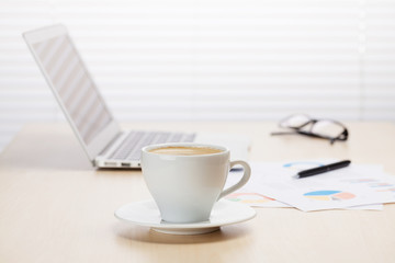 Office workplace with coffee, laptop and supplies