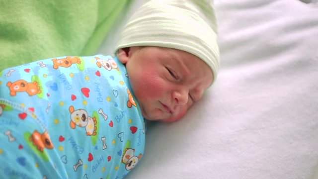 Newborn baby in hospital room. Infant sleeping in bedside bassinet. Little boy