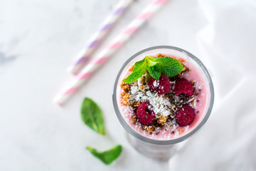 Yogurt granola parfait with frozen raspberries,сoconut flakes аnd сhia seeds, layered dessert or breakfast. Selective focus.Top view.