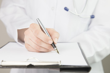 Close-up view of female doctor hands filling patient registration form. Healthcare and medical...