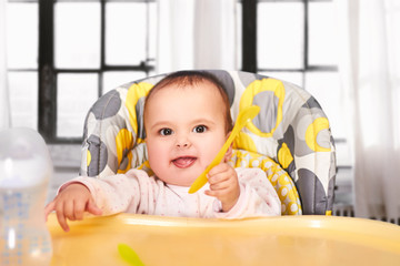 funny baby child sitting in chair with spoon