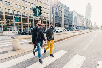 Two young bearded business man outdoor in the city walking - friendship, business concept