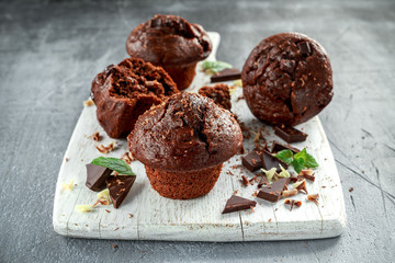 Brown muffins with dark chocolate chippings on white wooden board