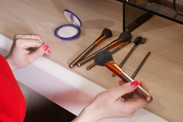 set of makeup brushes scattered randomly on the wooden background,