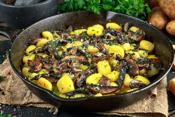Home made potato gnocchi with mushrooms, chopped parsley and parmesan cheese in iron pan