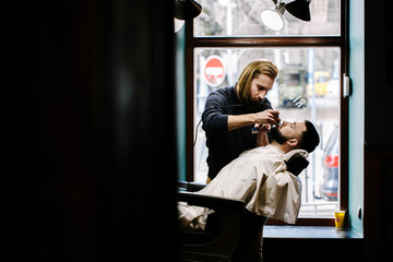 Look from afar at barber working with a client in a chair