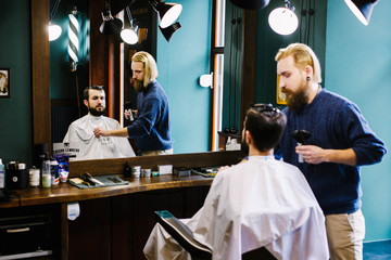 Blond barber fixes cloth on the client