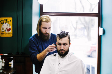 Barber cuts man's hair attentively