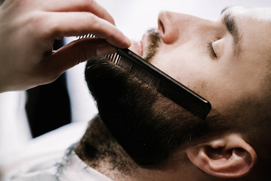 Barber brushes man's black beard