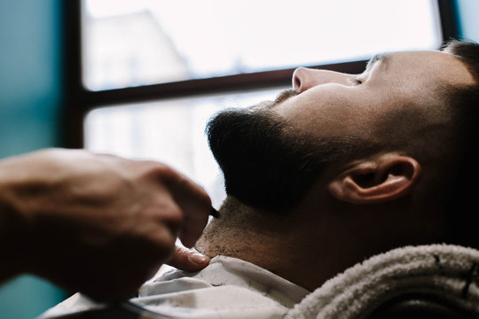 Barber cleans hair off man's neck