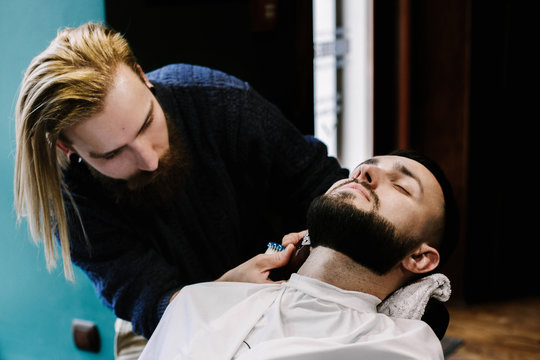 Barber cleans hair off man's neck