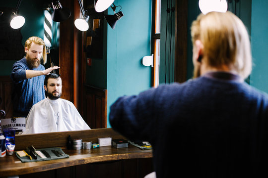 Stylish blond barber does man's hair in barbershop