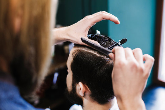 Barber makes clean sectioning before cuttin man's hair