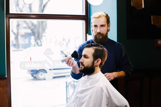 Blond barber cleans man's face with a brush