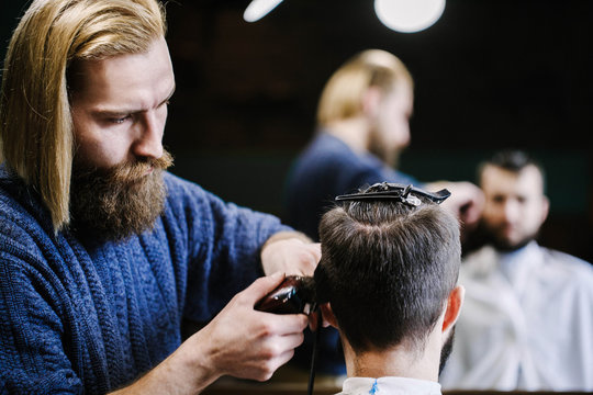 Barber cuts man's hair with clipper and brush