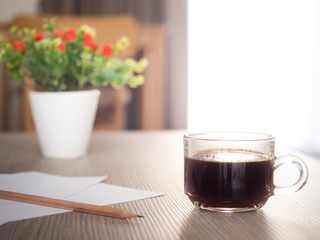 A cup of coffee and notebook on wood table . Coffee break in morning ,break working  / selective focus.Blank seating  indoor in living room .copy space for create idea for business.