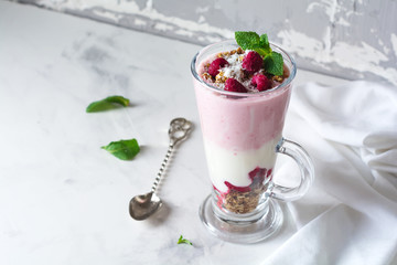 Yogurt granola parfait with frozen raspberries,сoconut flakes аnd сhia seeds, layered dessert or breakfast. Selective focus.