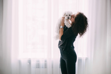 Curly woman in black embraces little fluffy dog