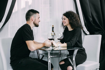 Man and woman drink wine sitting at little glass table