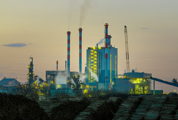 Cellulose Factory with wood in front by sunset