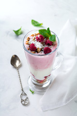 Yogurt granola parfait with frozen raspberries,сoconut flakes аnd сhia seeds, layered dessert or breakfast. Selective focus.