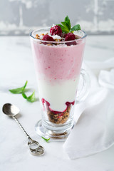 Yogurt granola parfait with frozen raspberries,сoconut flakes аnd сhia seeds, layered dessert or breakfast. Selective focus.