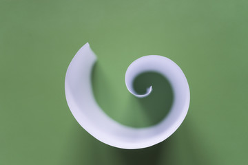 Curled paper fractal/White paper sheet spiral resembling the golden ratio proportion on a green...
