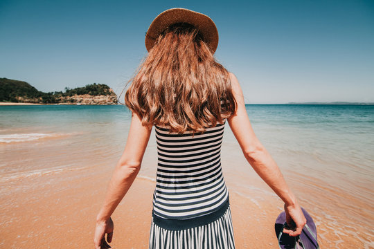 Woman in her back entering into a beautiful Australian beach blue water.