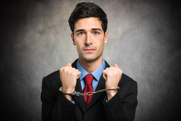 Manager in handcuffs in his office looking sad