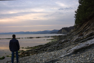 On the beach at sunset a man is standing