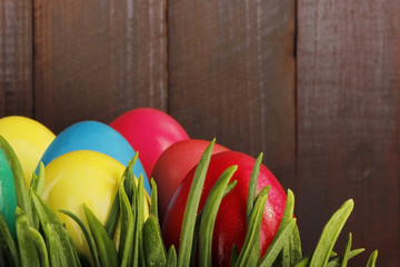 coloured eggs in grass on wooden background