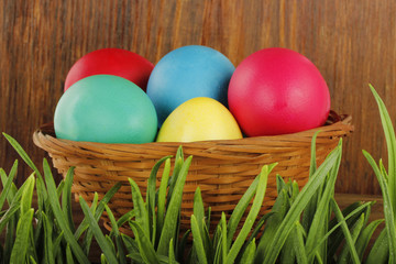 coloured eggs in grass on wooden background