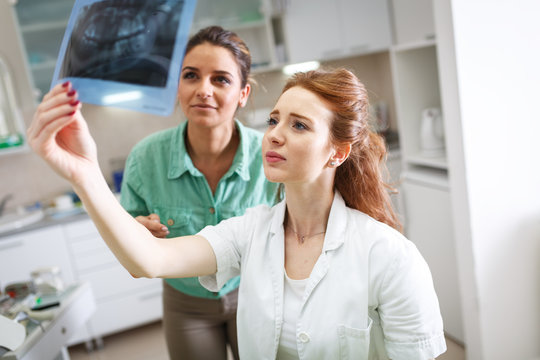 Two female dentist in dental office examining x-ray image.