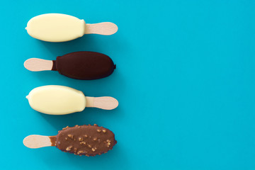 Black and white chocolate ice cream popsicles on blue background. 

