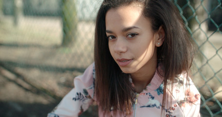Young beautiful woman wearing bomber jacket posing over metal fence. Portrait of a young African...