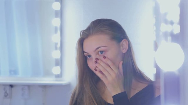 Portrait of pretty, young and sensual woman without makeup looking at her reflection in mirror and fixing hair. Natural beauty concept